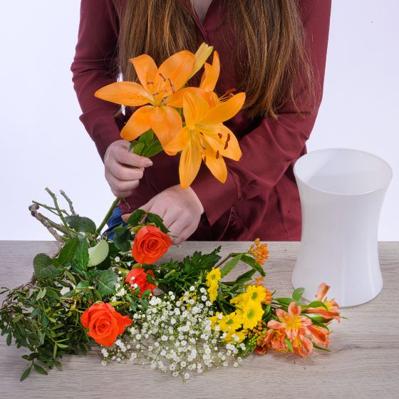 orange Lillien, orange Rosen, gelbe Chrysanthemen und Schleierkraut
